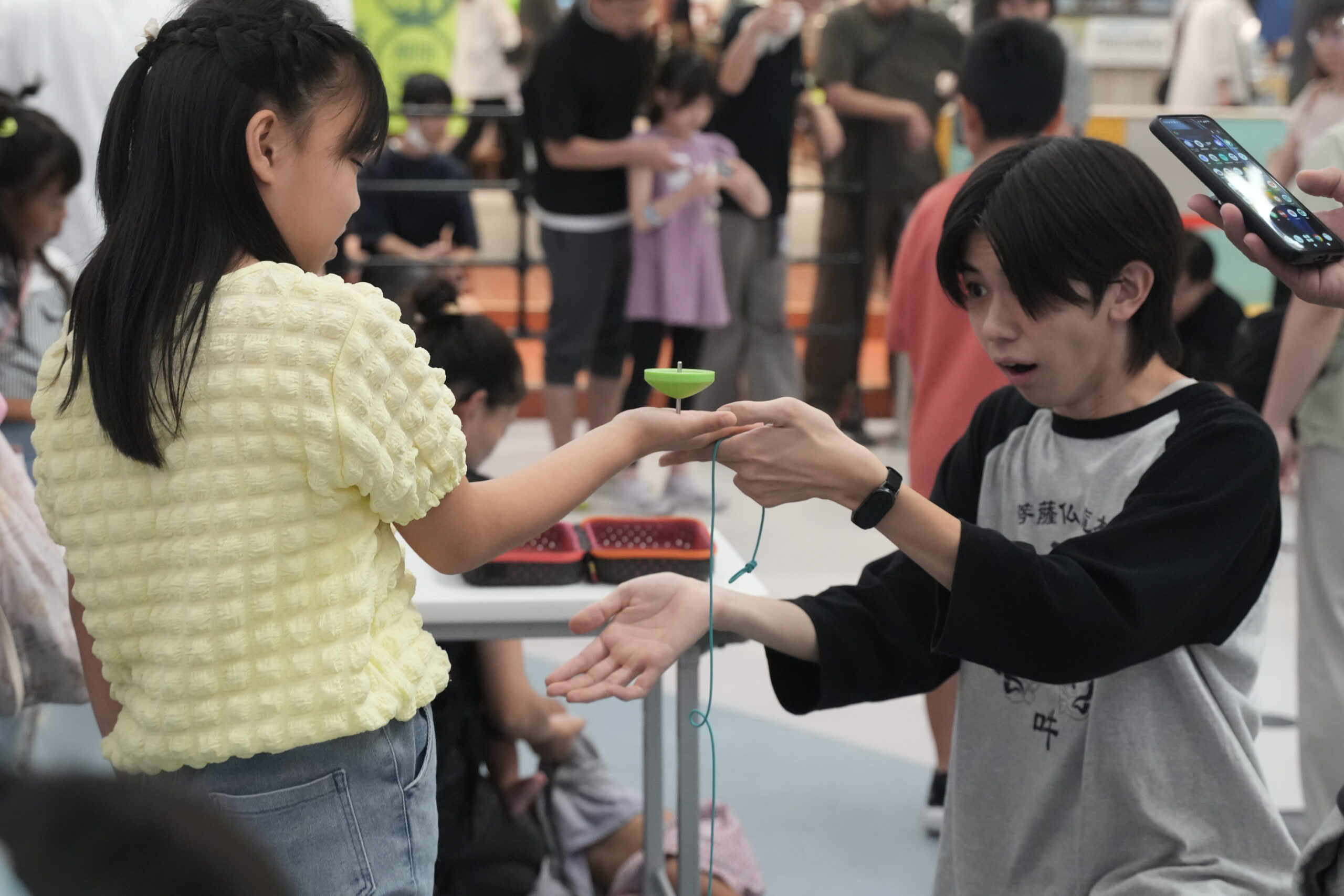 講師のサポートを受け、手のひらでコマを回す体験